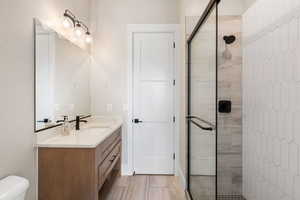 Full bathroom featuring a stall shower, vanity, and light wood-style flooring