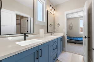 Full bath with healthy amount of natural light, double vanity, connected bathroom, and light tile patterned floors