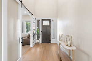 Entrance foyer with a barn door, wood finished floors, and a high ceiling