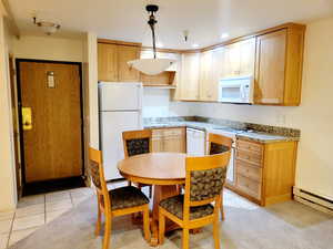 Kitchen featuring white appliances, light tile patterned flooring, pendant lighting, light stone counters, and recessed lighting