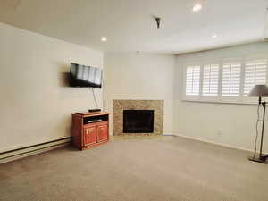 Unfurnished living room with a fireplace, carpet floors, recessed lighting, and a baseboard radiator