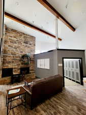 Living room with beam ceiling, wood finished floors, high vaulted ceiling, and a fireplace