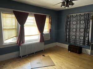 Primary bedroom featuring radiator and light wood finished floors