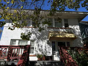 View of front of property with brick siding and a wooden deck