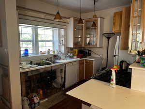 Kitchen featuring light countertops, hanging light fixtures, glass insert cabinets, black gas stove, and dishwasher, cabinet doors are missing