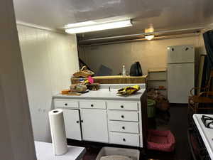 Kitchen with white cabinetry, white appliances, light countertops, and wood walls