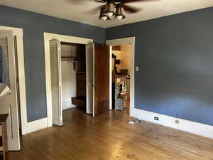 Unfurnished bedroom featuring hardwood / wood-style flooring, multiple closets, and ceiling fan