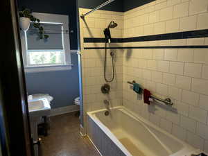 Bathroom featuring tiled shower / bath combo and toilet