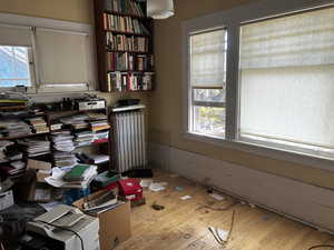 Office space with radiator heating unit, light wood finished floors, and healthy amount of natural light