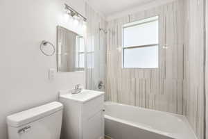 Full bathroom with washtub / shower combination, vanity, and healthy amount of natural light