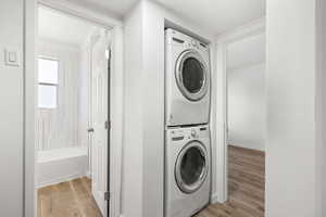Laundry area featuring light wood-style flooring and stacked washer / dryer