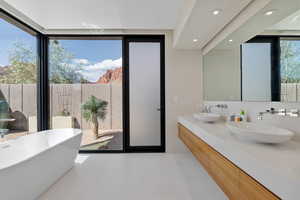 Bathroom featuring a freestanding bath, double vanity, recessed lighting, and light tile patterned floors