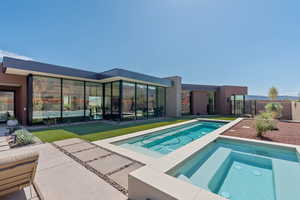 Rear view of property with an in-ground hot tub and a patio area