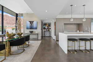 Kitchen featuring a breakfast bar, modern cabinets, hanging light fixtures, finished concrete floors, and recessed lighting