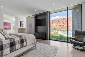 Bedroom featuring expansive windows, access to exterior, recessed lighting, and finished concrete floors