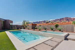View of pool featuring a fenced backyard, a mountain view, a jacuzzi, and a patio area