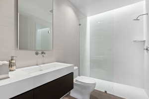 Bathroom with tile walls, walk in shower, and vanity