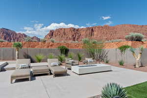 Fenced backyard featuring a mountain view, a patio area, and an outdoor living space with a fire pit