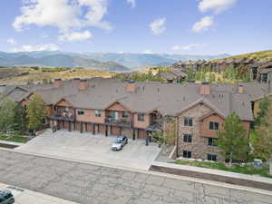 View of front of house with stone siding, a residential view, a mountain view, and driveway