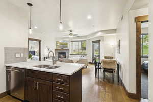 Kitchen featuring hanging light fixtures, open floor plan, a glass covered fireplace, dark brown cabinets, and light wood-style flooring