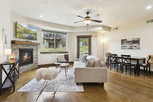 Living room with recessed lighting, wood finished floors, a ceiling fan, and a stone fireplace