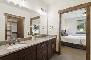 Ensuite bathroom with double vanity, a ceiling fan, and a closet