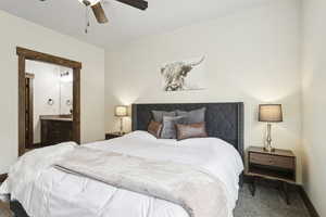 Carpeted bedroom featuring connected bathroom and a ceiling fan