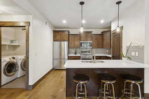 Kitchen with decorative backsplash, stainless steel appliances, a peninsula, a kitchen bar, and light wood-type flooring