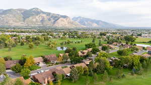 Aerial overview of property's location with nearby suburban area, a water and mountain view, and a local golf course