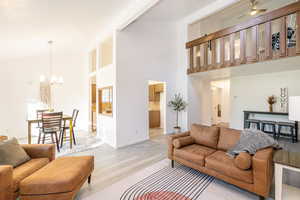 Living room with wood finished floors, high vaulted ceiling, ceiling fan, and a chandelier