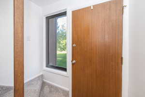 Doorway with carpet floors and baseboards