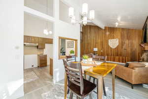 Dining room featuring wood walls, light wood-type flooring, and a chandelier