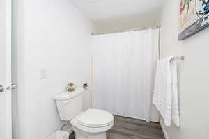 Full bathroom with dark wood-type flooring and a shower with curtain