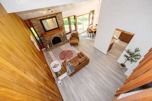 Living area with a textured ceiling, a brick fireplace, light wood-style flooring, and plenty of natural light