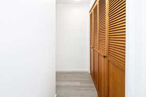 Corridor with light wood-type flooring and baseboards