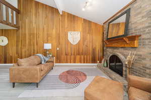 Living area with a fireplace, wood walls, and wood finished floors
