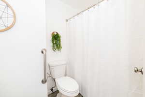 Full bathroom with toilet and curtained shower