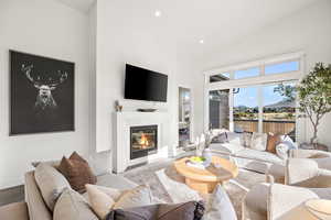 Living room featuring recessed lighting, a glass covered fireplace, high vaulted ceiling, and wood finished floors
