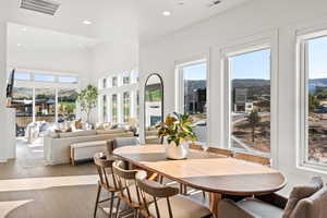 Dining area featuring recessed lighting, healthy amount of natural light, hardwood / wood-style flooring, and a towering ceiling