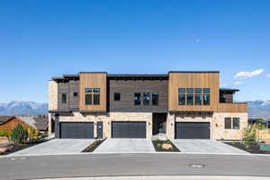 Contemporary home with a mountain view, stone siding, concrete driveway, and a garage