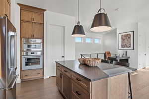 Kitchen featuring a kitchen bar, brown cabinets, appliances with stainless steel finishes, dark wood finished floors, and a center island