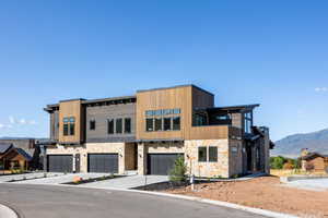 Contemporary house with a mountain view, a garage, driveway, and stone siding