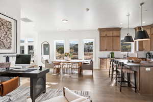 Kitchen featuring a kitchen breakfast bar, hanging light fixtures, light wood-style floors, backsplash, and brown cabinetry
