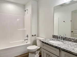Bathroom with tub / shower combination, vanity, and dark wood-style flooring