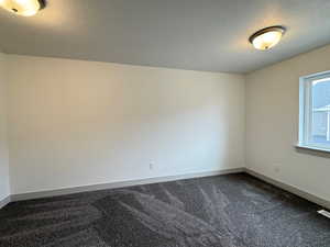 Bedroom with a textured ceiling and dark colored carpet