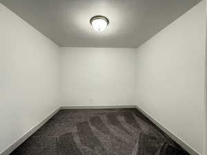 Spare room with dark carpet and a textured ceiling