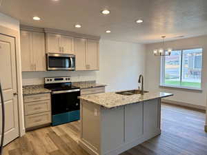 Kitchen featuring stainless steel appliances, light stone countertops, recessed lighting, light wood-style floors, and hanging light fixtures