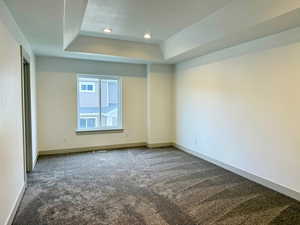Primary bedroom with carpet, a tray ceiling, and recessed lighting