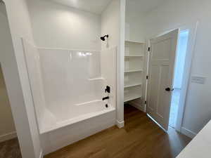 Full bathroom featuring bathtub / shower combination, wood finished floors, vanity and ample storage