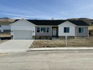 View of front of house with concrete driveway, a garage, a mountain view, and roof with shingles